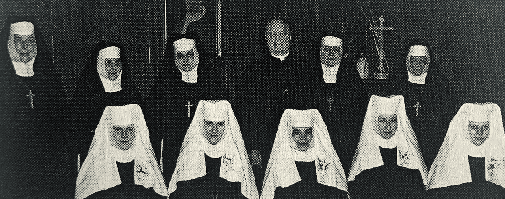 A group picture in a church of five novices in the front row and five sisters and a priest standing in the back row.